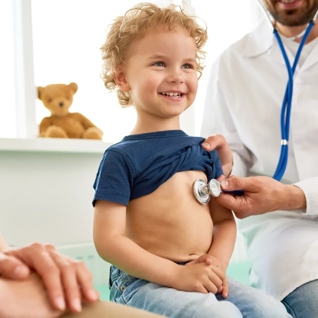 Family medicine doctor in Chicago listening to young child’s chest with a stethoscope during checkup 