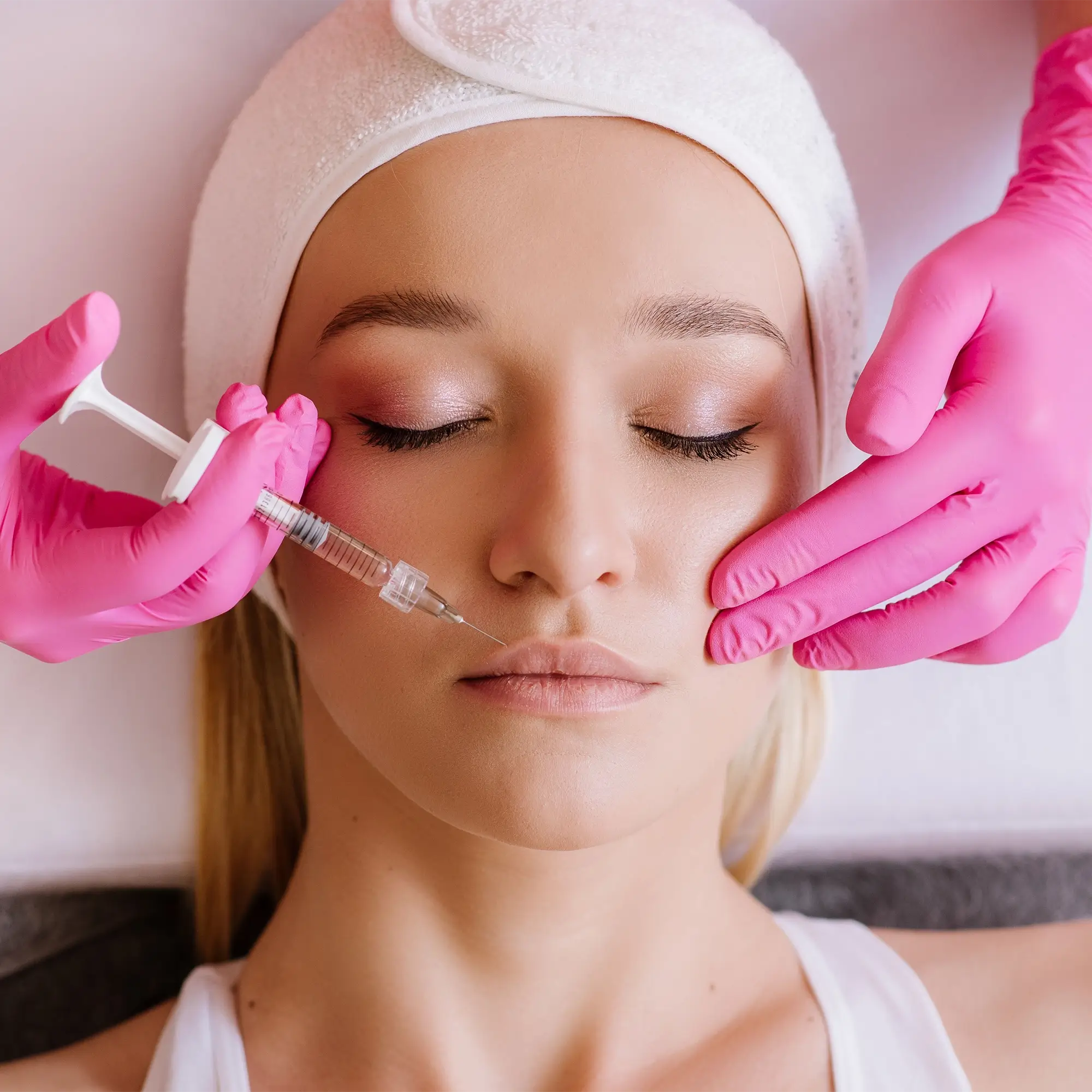 Clinician in pink gloves performing lip filler injections to enhance lip volume 