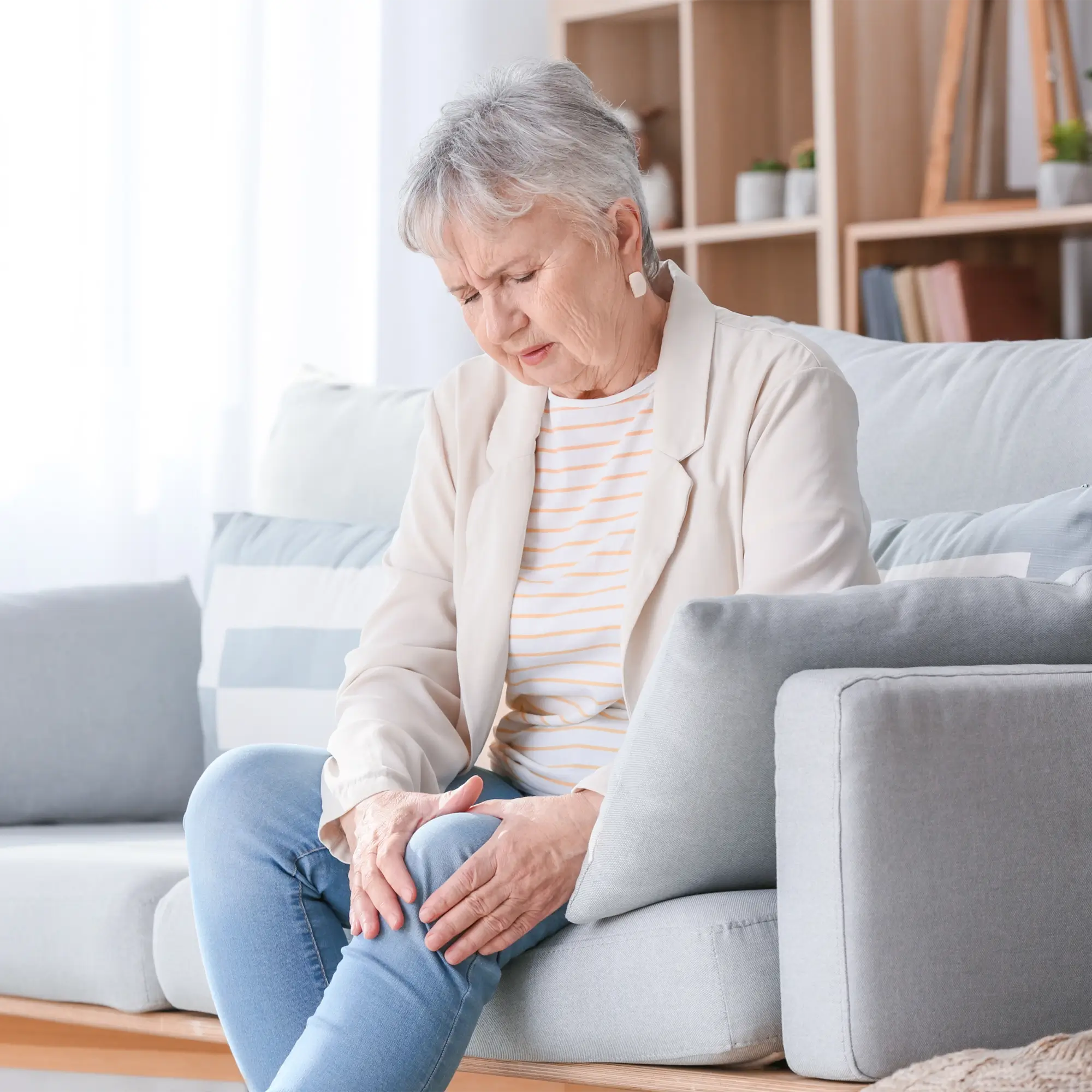 Middle aged women sitting and holding his painful knee while considering hyaluronic acid injections